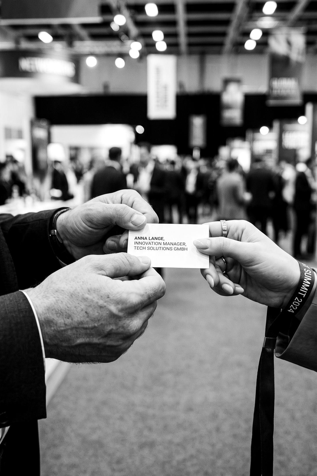 Übergabe einer Visitenkarte auf einer Fachmesse, Schwarz-Weiß