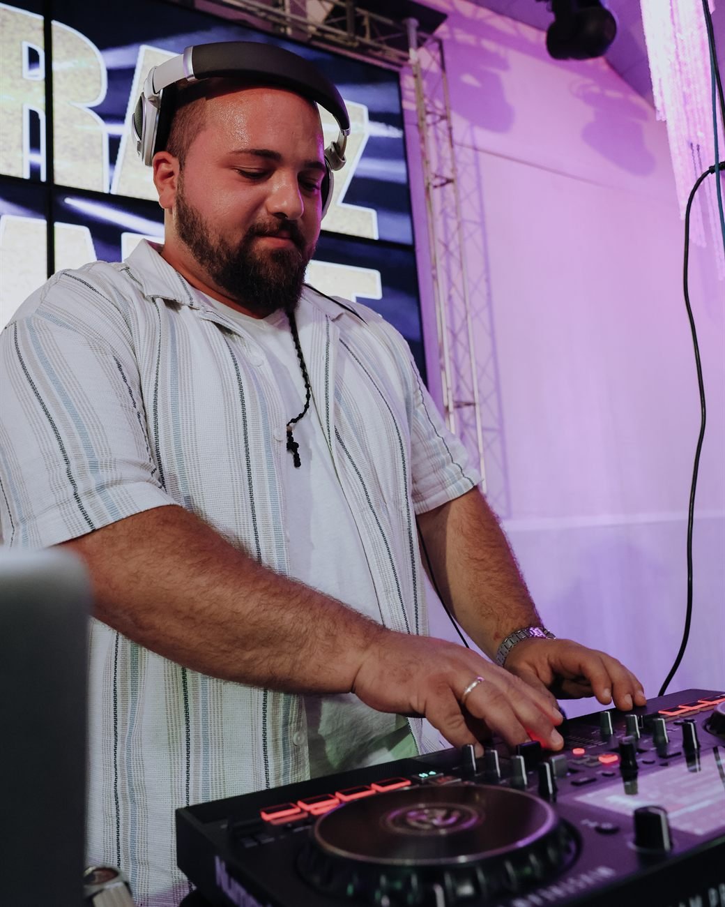 DJ Stelios Pappas mit Kopfhörern am DJ-Pult, im Hintergrund violettes Bühnenlicht