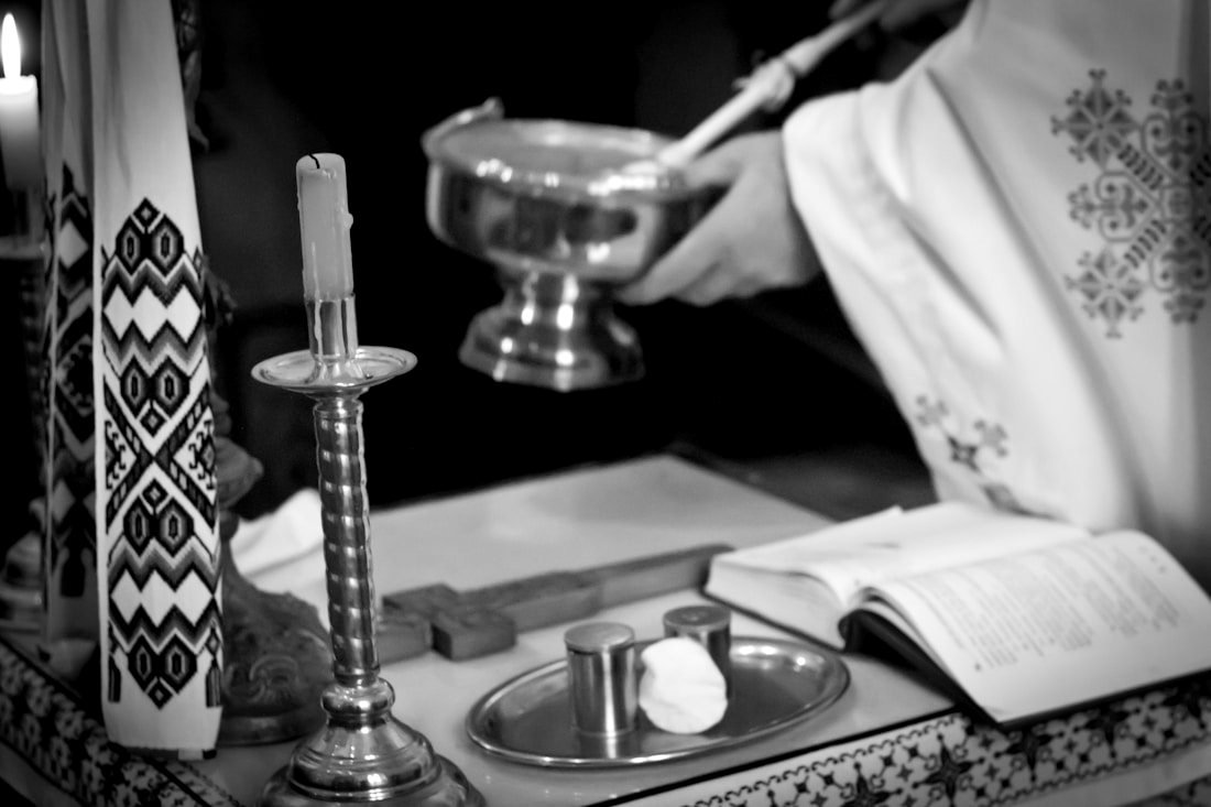Orthodoxer Priester mit Weihrauchgefäß und Kerze am Taufaltar, Schwarz-Weiß